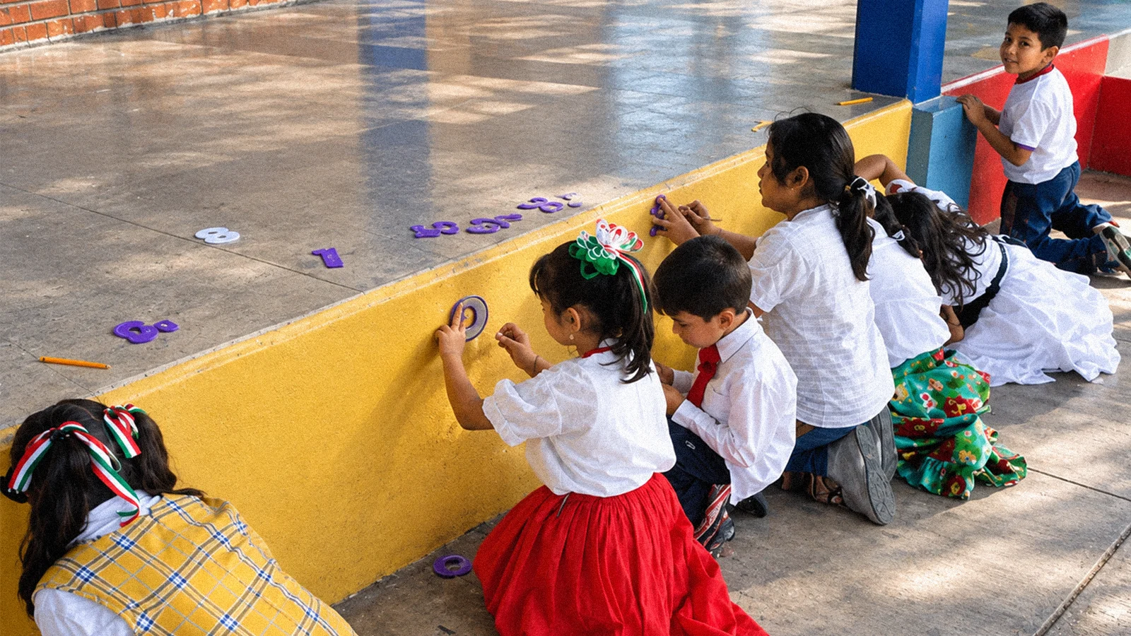 Alumnas realizan una actividad manual junto a un muro amarillo.